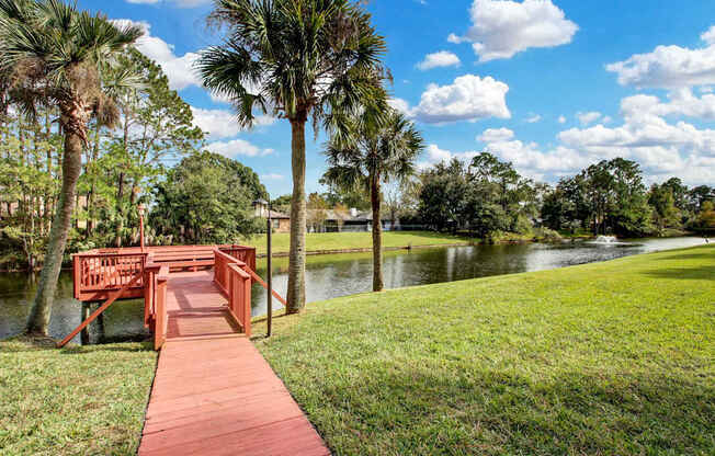A wooden bridge over a body of water with palm trees in the background.
