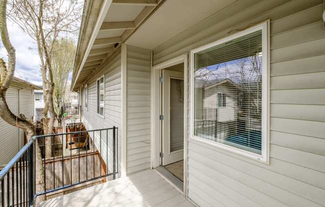 a front porch with a black railing and a white house in the background