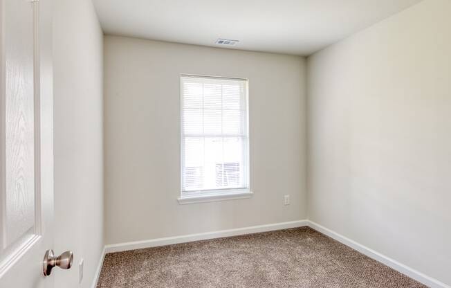 an empty bedroom with white walls and a window