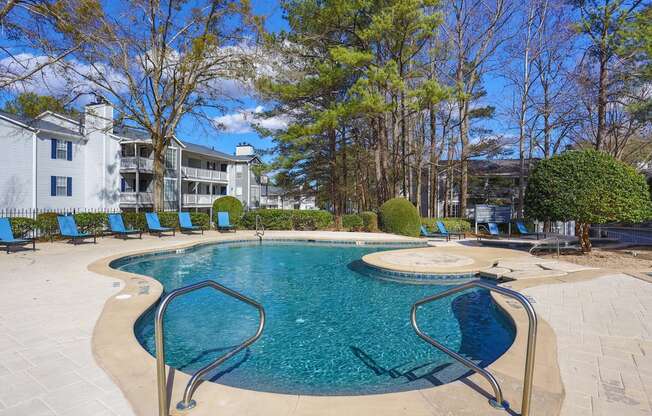 a swimming pool with blue chairs and a building in the background