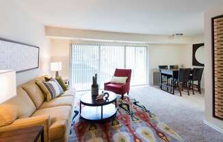 A living room with a couch, a chair, a coffee table, and a dining table.