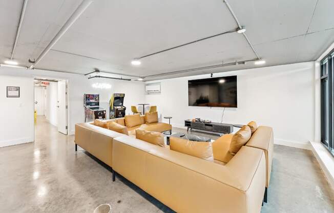 A living room with a tan couch and a television mounted on the wall.