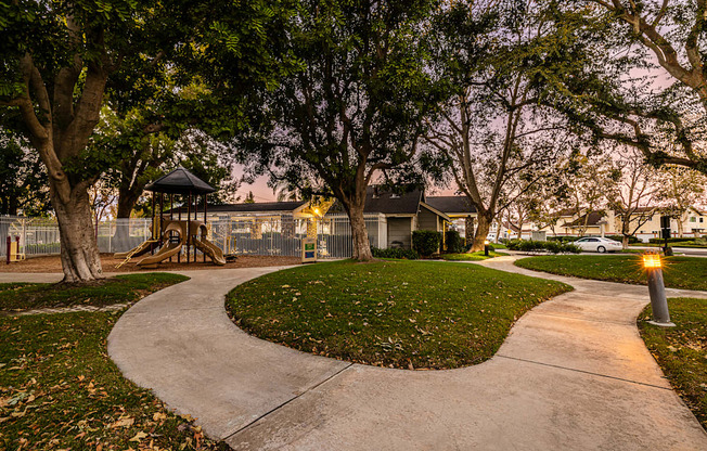 a walkway through a park with a playground and trees