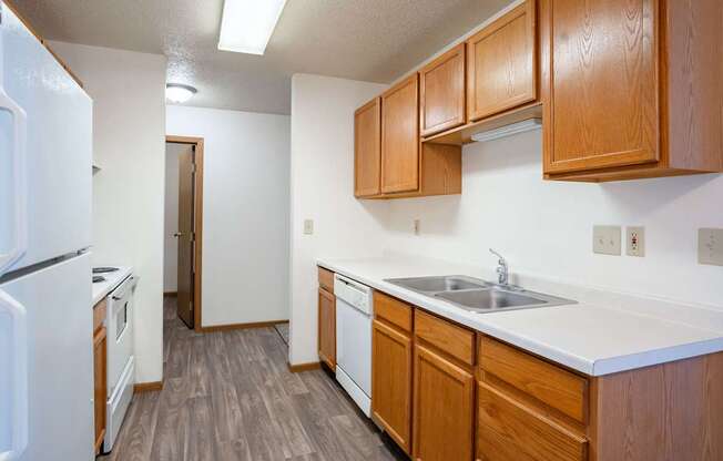A kitchen with wooden cabinets and a white refrigerator. Fargo, ND Country Edge Apartments