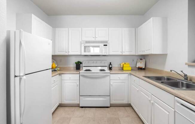 A white kitchen with a refrigerator, oven, and microwave.