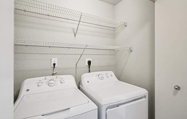 Two white front loading washing machines in a laundry room.