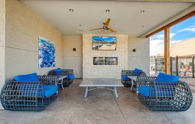 a patio with blue chairs and a table and a ceiling fan