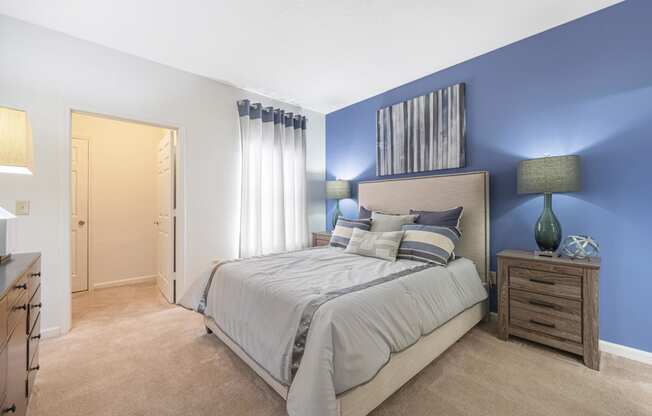 furnished bedroom with blue accent wall and a bed with white comforter