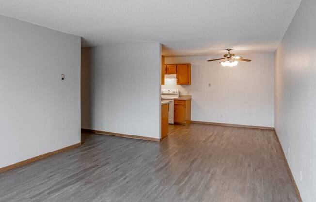 the living room and kitchen of an empty house with wood flooring