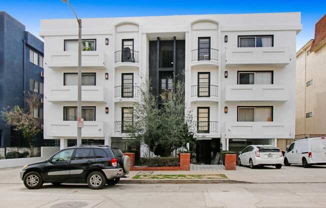 a white apartment building with cars parked in front of it