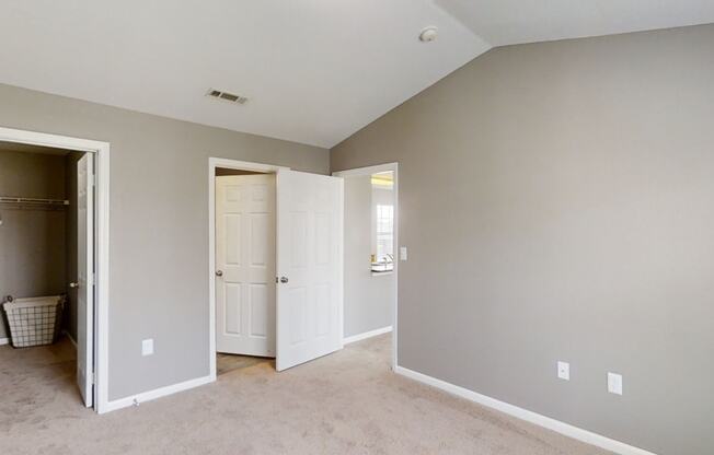 A bedroom with a closet and a door to a bathroom