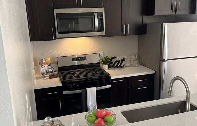 a kitchen with black cabinets and stainless steel appliances