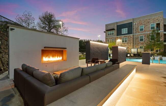 A modern outdoor seating area with a fireplace is set up on a patio.