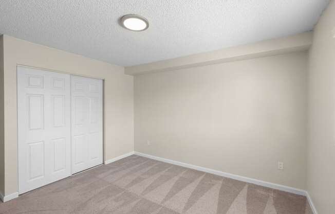 a bedroom with a white closet doors and tan carpeting at Park Edmonds Apartment Homes, Edmonds, 98026
