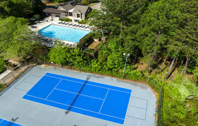 Vinings, GA Pet-Friendly Apartments - Wynnwood Vinings - Pool Area with Lounge Chairs and Two Tennis Courts, Surrounded by Beautiful Landscaping