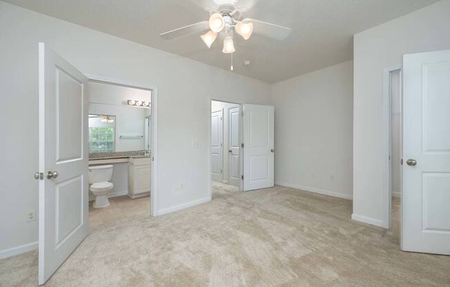A spacious room with a ceiling fan and carpeted floor.