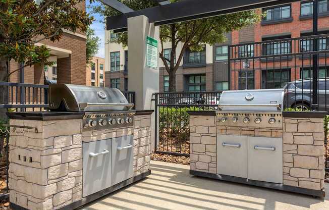 Two stone BBQs are in a sunny courtyard.