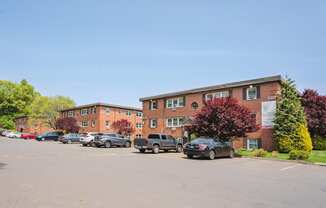 a parking lot with cars in front of an apartment building at Springwood Gardens, Connecticut, 06053