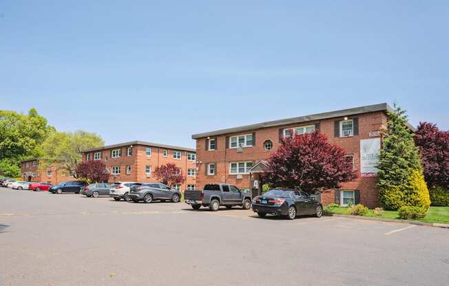 a parking lot with cars in front of an apartment building at Springwood Gardens, Connecticut, 06053