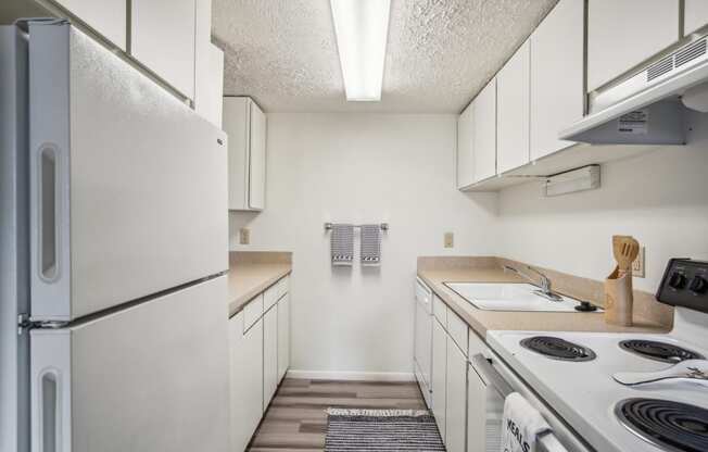 an empty kitchen with white appliances and white cabinets