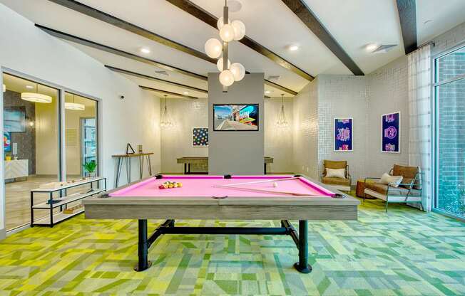 A pool table in a room with a TV on the wall.