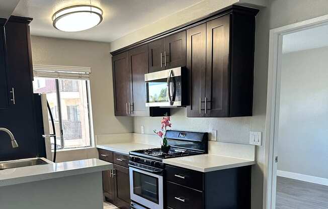 A modern kitchen with dark wood cabinets and a white ceiling.