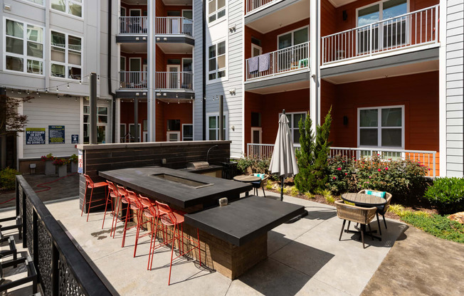 an outdoor patio with a firepit and tables and chairs in front of an apartment building  at Abberly Noda Vista Apartment Homes, Charlotte, NC, 28206