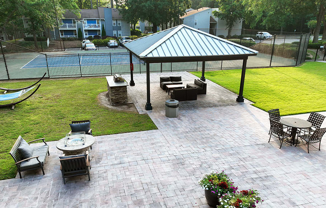a large paver patio with a gazebo and a hammock next to a