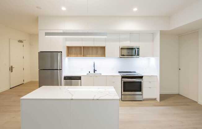 A modern kitchen with a refrigerator, microwave, oven, and sink.at The Dillon, Los Angeles