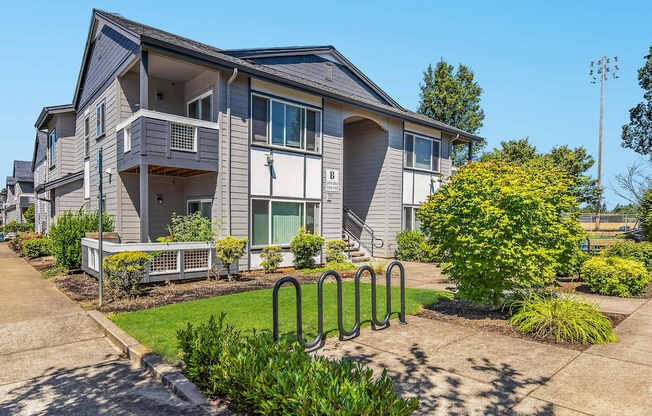 A modern two-story apartment building with bike racks and a clear blue sky at The Landing Apartments and Townhomes, Oregon, 97045