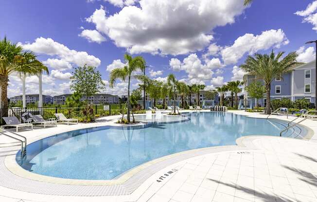 a large swimming pool with palm trees and buildings in the background