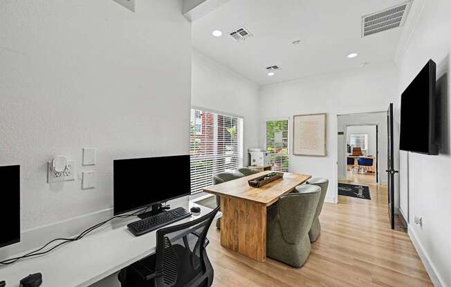 A modern home office with a desk, chairs, and computer monitors.