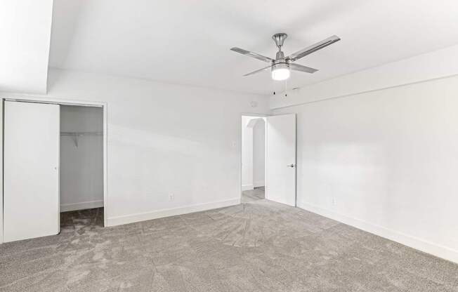 A room with a ceiling fan and carpeted floor.