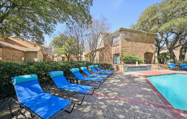 A pool surrounded by blue lounge chairs.