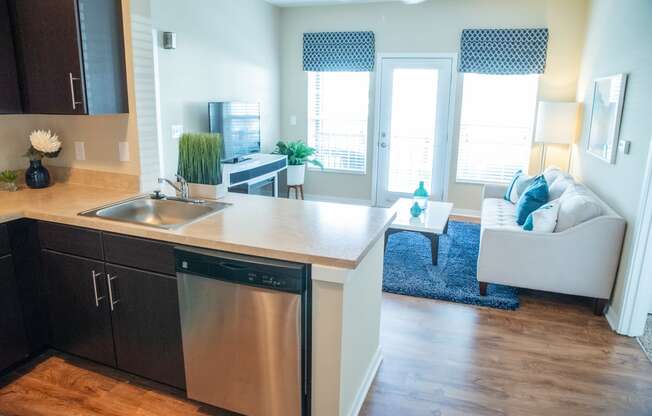 a kitchen with a dishwasher and sink and a living room with a couch