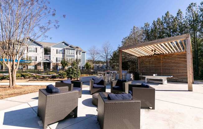 a patio with chairs and tables and a wooden structure