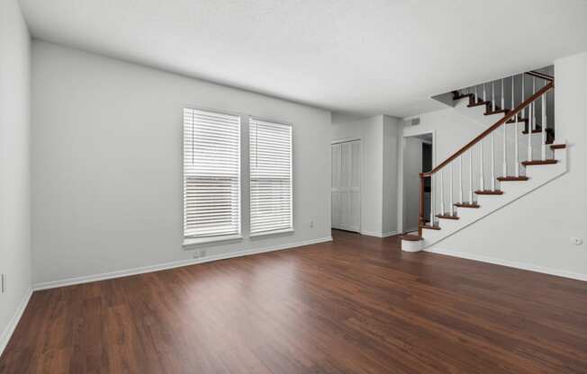 an empty living room with hard wood floors and a staircase