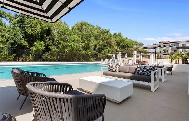 a poolside patio with chairs and tables and a pool