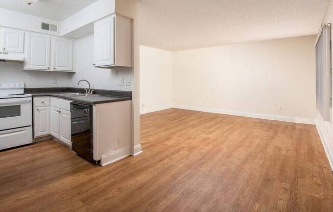 an empty kitchen with white cabinets and a wood floor