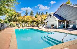 A swimming pool in front of a house with trees in the background.