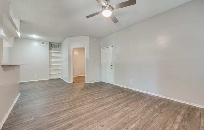 an empty living room with wood flooring and a ceiling fan