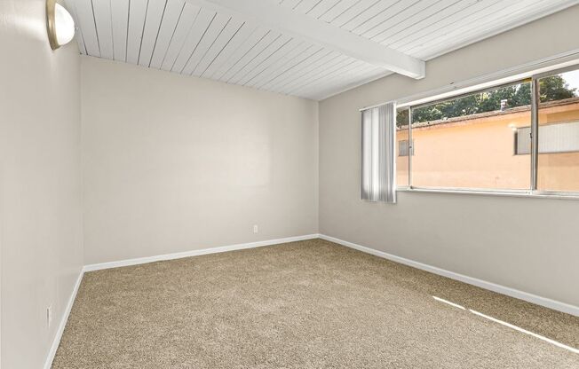 Empty room with carpeted floor and a window.