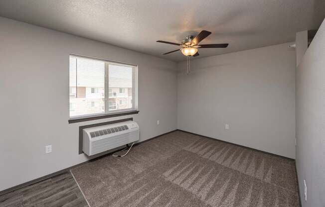 A room with a ceiling fan and carpeted floor.