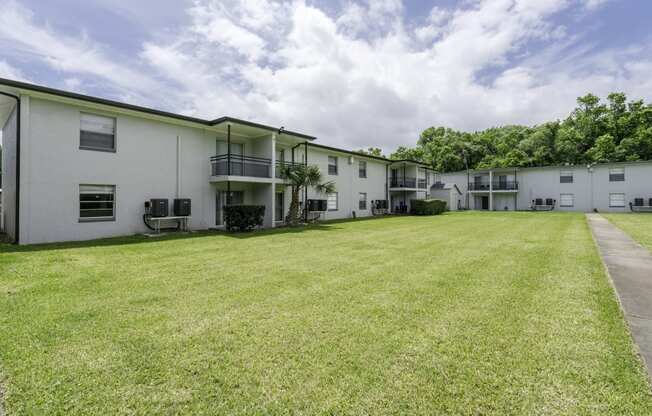 the outlook of an apartment building with a large grass yard