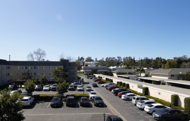 A parking lot with cars and apartment buildings in the background.