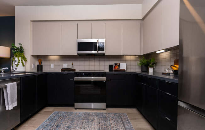 A modern kitchen with black cabinets and stainless steel appliances.