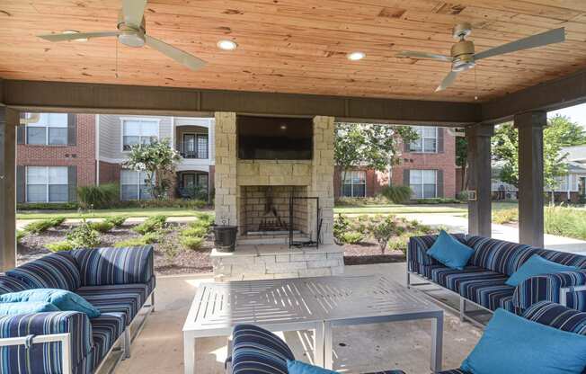 a covered patio with couches and a fireplace