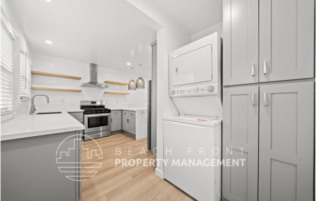 a white and gray kitchen with white appliances and white cabinets