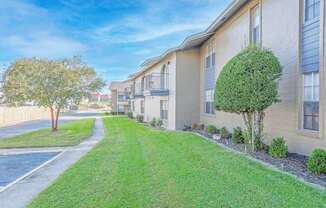 Apartment buildings with second-floor balconies and green grass outside   at The Creole Apartments in Shreveport, LA