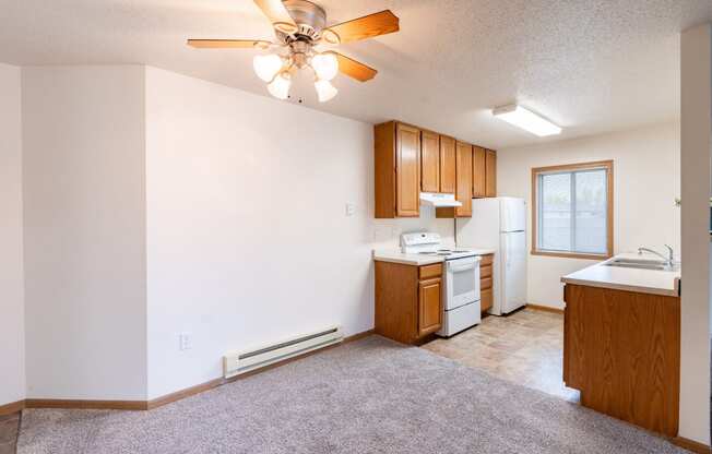 a dining room with a kitchen and a ceiling fan. Fargo, ND Oxford Apartments